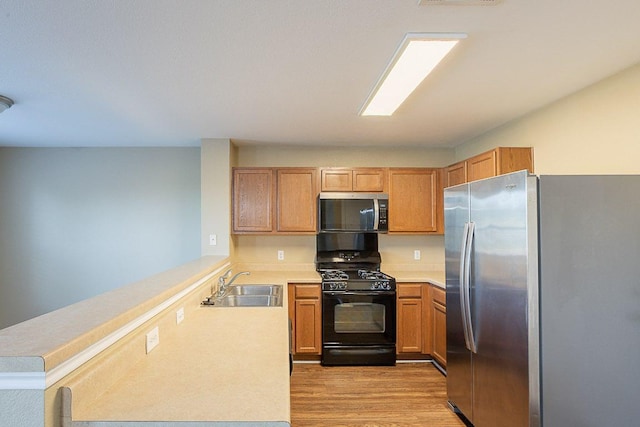 kitchen with a sink, a peninsula, stainless steel appliances, light wood-type flooring, and light countertops