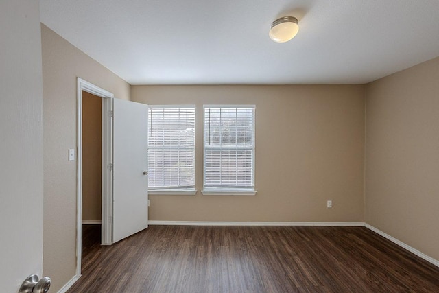 spare room featuring dark wood finished floors and baseboards