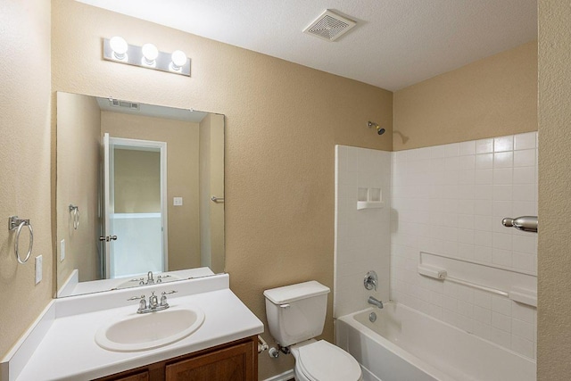 bathroom with vanity, toilet, a textured wall, and visible vents