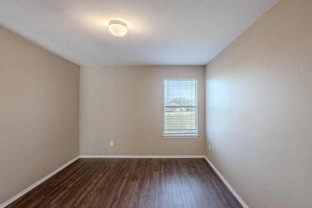 empty room with baseboards and dark wood finished floors