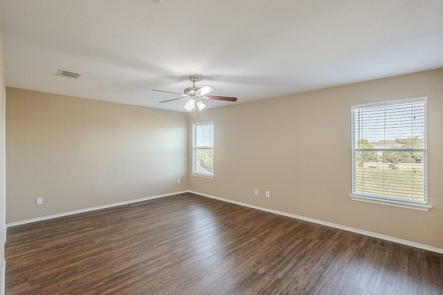 spare room with baseboards, dark wood-style flooring, visible vents, and ceiling fan