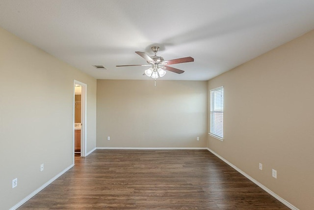 unfurnished room featuring baseboards, a ceiling fan, visible vents, and dark wood finished floors