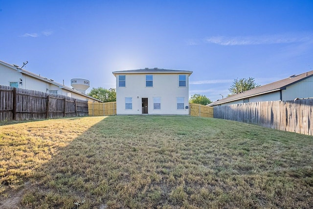 back of property featuring a yard, stucco siding, and a fenced backyard