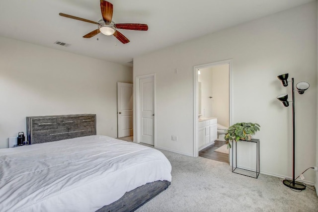 bedroom featuring ensuite bathroom, visible vents, baseboards, ceiling fan, and light carpet