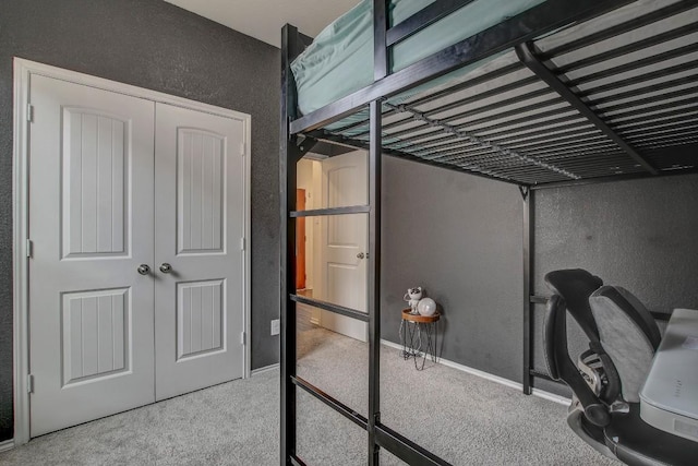 carpeted bedroom with a closet, baseboards, and a textured wall