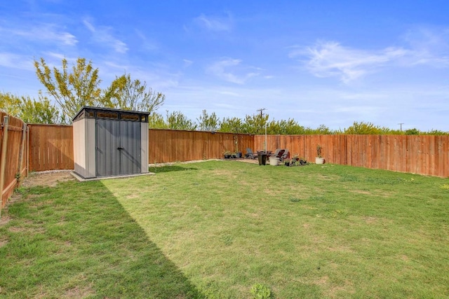 view of yard with an outbuilding, a fenced backyard, and a storage unit
