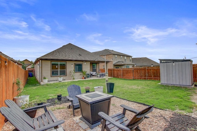 rear view of property with an outdoor fire pit, a patio, a fenced backyard, and a storage unit