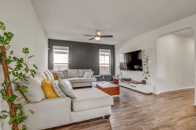 living area with baseboards, a ceiling fan, and wood finished floors