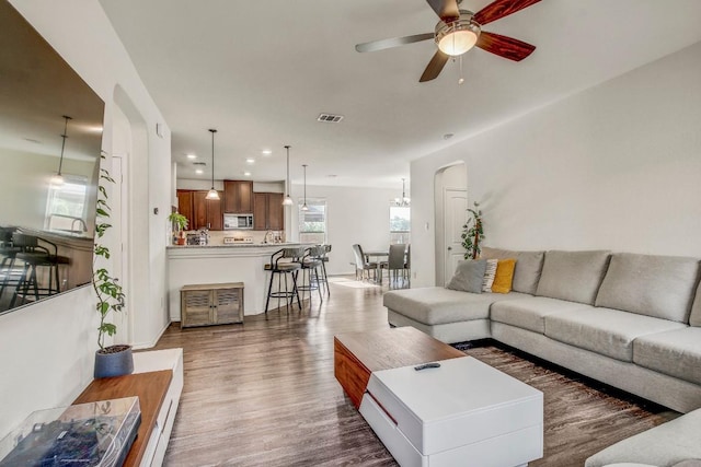 living area featuring recessed lighting, dark wood finished floors, ceiling fan, visible vents, and arched walkways