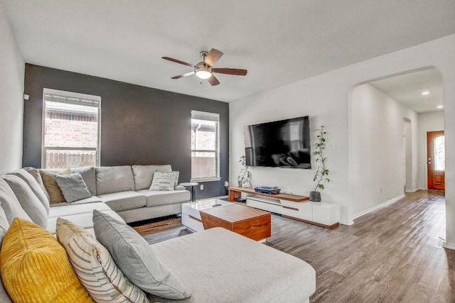living area with a ceiling fan, baseboards, plenty of natural light, and wood finished floors