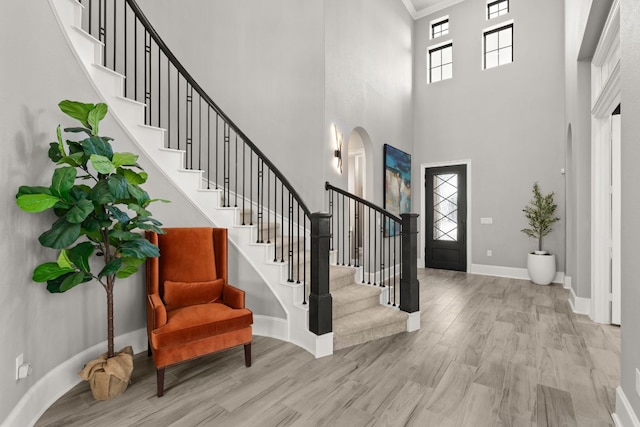 entrance foyer featuring wood finished floors, stairway, baseboards, and a high ceiling