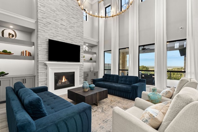living area featuring an inviting chandelier, wood finished floors, built in features, a towering ceiling, and a large fireplace