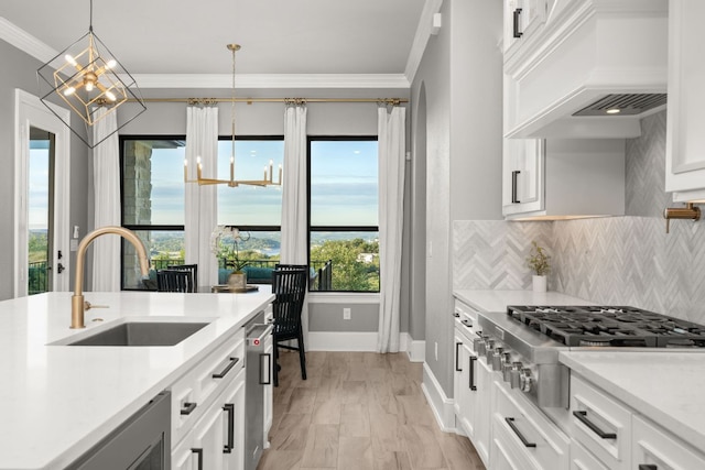 kitchen featuring light countertops, stainless steel gas stovetop, crown molding, and a sink