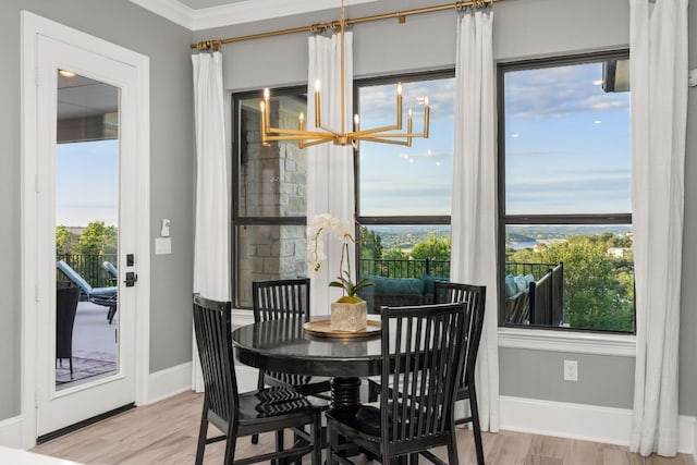 dining room featuring crown molding, wood finished floors, baseboards, and a notable chandelier