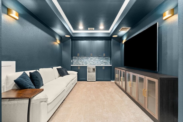 cinema featuring wine cooler, a tray ceiling, wet bar, crown molding, and light carpet