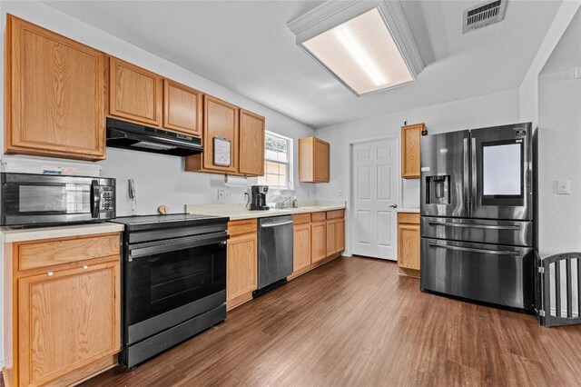 kitchen with under cabinet range hood, visible vents, dark wood-type flooring, light countertops, and appliances with stainless steel finishes