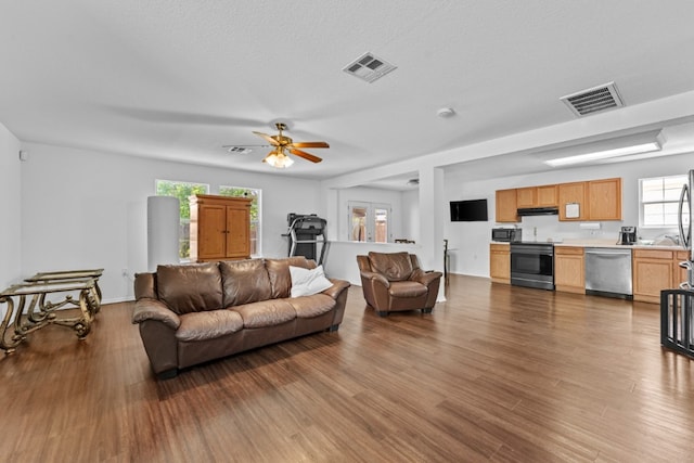 living area with ceiling fan, visible vents, and wood finished floors
