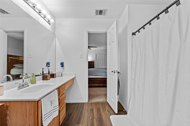 ensuite bathroom featuring vanity, connected bathroom, visible vents, and wood finished floors