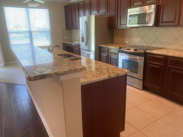 721 Independence Creek Ln, Georgetown, TX 78633 - kitchen with a sink, a center island with sink, backsplash, appliances with stainless steel finishes, and light stone counters