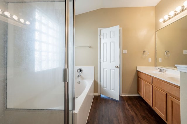 13605 James Garfield St, Manor, TX 78653 - bathroom with a garden tub, wood finished floors, baseboards, vaulted ceiling, and vanity
