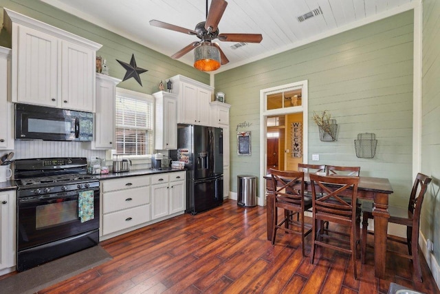 1200 County Road 211, Giddings, TX 78942 - kitchen with wood walls, black appliances, dark wood finished floors, white cabinets, and dark countertops