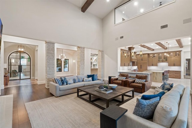 5609 Laceback Ter, Austin, TX 78738 - living room with ornate columns, beamed ceiling, high vaulted ceiling, a chandelier, and light wood-style flooring