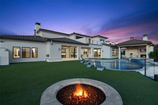 5609 Laceback Ter, Austin, TX 78738 - back of property at dusk featuring a lawn, a chimney, a patio, and a pool with connected hot tub