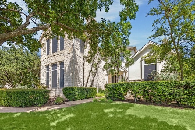 view of side of home with a yard and stone siding