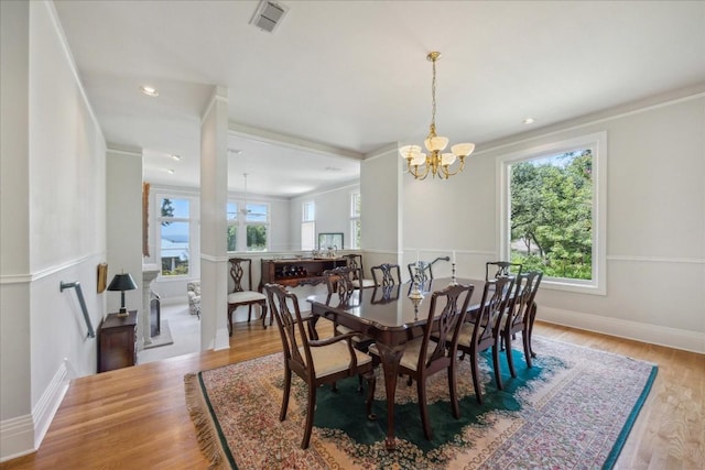 dining space featuring baseboards, visible vents, a chandelier, crown molding, and wood finished floors