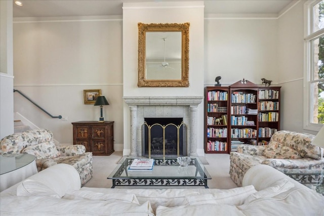 carpeted living area with crown molding, a fireplace, and ceiling fan