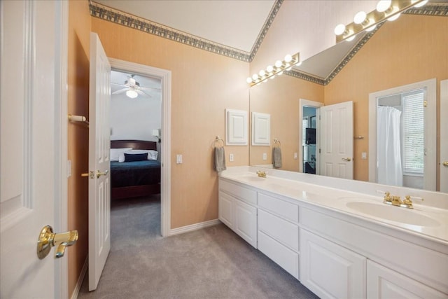 full bathroom with double vanity, ensuite bathroom, vaulted ceiling, and a sink