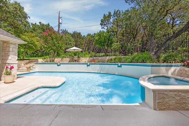 outdoor pool with a patio area and an in ground hot tub
