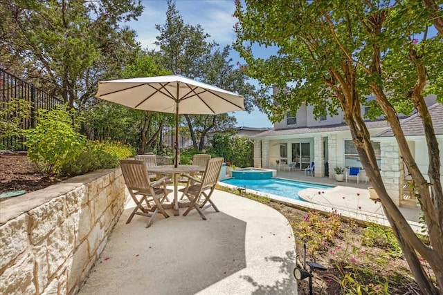 view of pool with a patio area, a pool with connected hot tub, fence, and outdoor dining space