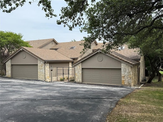 view of front facade featuring stone siding, a tiled roof, and fence