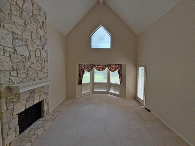 unfurnished living room featuring carpet, plenty of natural light, a stone fireplace, and high vaulted ceiling