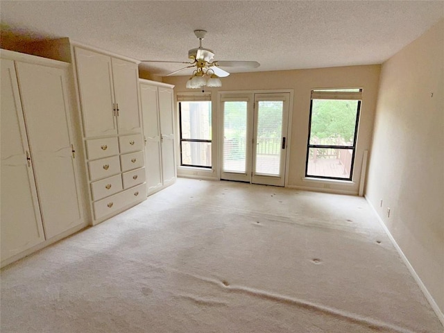 unfurnished room with light colored carpet, a textured ceiling, baseboards, and ceiling fan