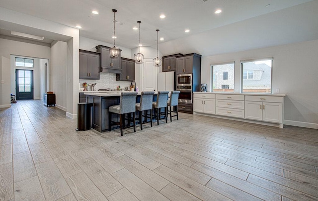 6320 Lipan Bayou Trl, Austin, TX 78738 - kitchen with light wood-type flooring, a kitchen breakfast bar, light countertops, tasteful backsplash, and recessed lighting