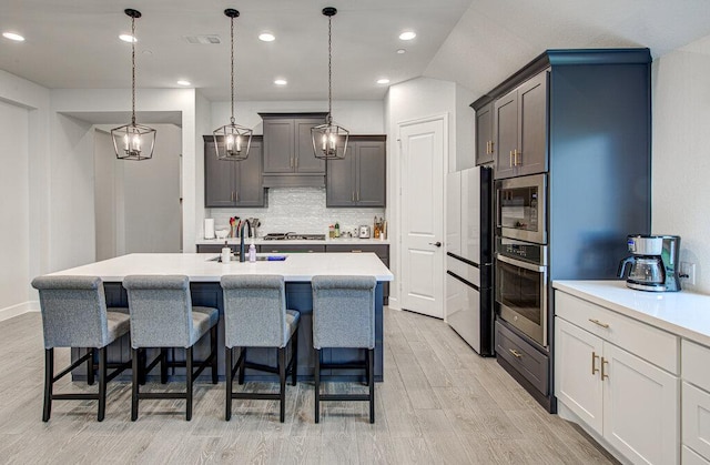 6320 Lipan Bayou Trl, Austin, TX 78738 - kitchen featuring appliances with stainless steel finishes, light wood-style flooring, a breakfast bar, tasteful backsplash, and recessed lighting