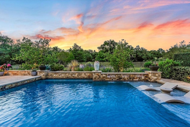 pool at dusk with a fenced in pool and a fenced backyard