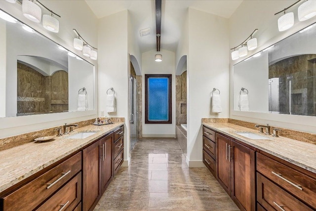 full bath featuring a shower stall, marble tiled floors, two vanities, and a garden tub