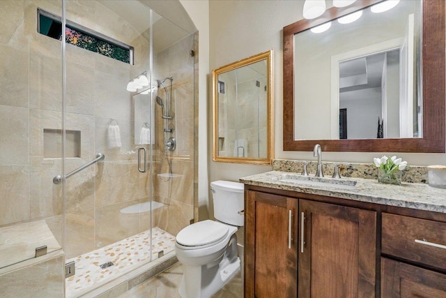 bathroom featuring toilet, vanity, and a stall shower