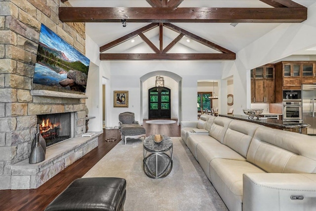 living room featuring arched walkways, a stone fireplace, wood finished floors, and recessed lighting