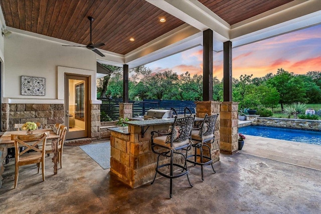 view of patio with a ceiling fan, fence, outdoor wet bar, area for grilling, and a fenced in pool