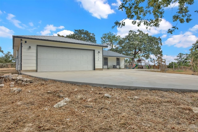 exterior space with metal roof, a playground, and a garage