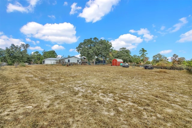 view of yard with a storage unit, an outdoor structure, and a playground
