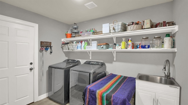 laundry area with wood finished floors, a sink, separate washer and dryer, laundry area, and visible vents