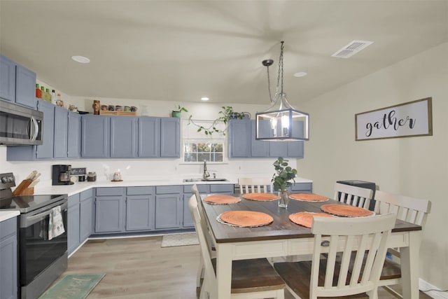kitchen with a sink, light wood-type flooring, visible vents, light countertops, and appliances with stainless steel finishes