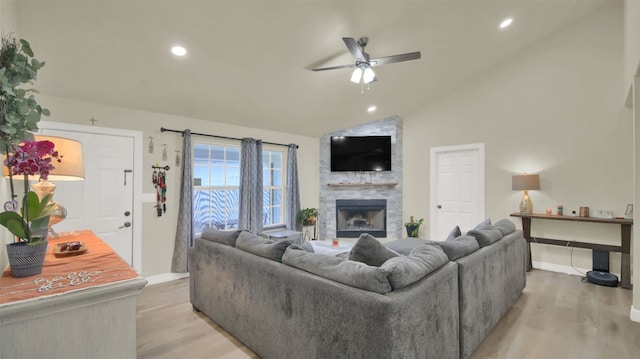 living room featuring light wood-style floors, baseboards, a ceiling fan, and a fireplace