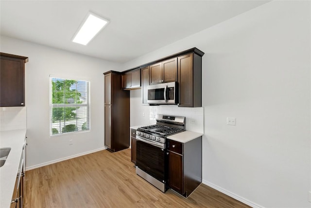7013 Tonka Ln, Austin, TX 78744 - kitchen with appliances with stainless steel finishes, tasteful backsplash, dark brown cabinetry, light countertops, and light wood-type flooring