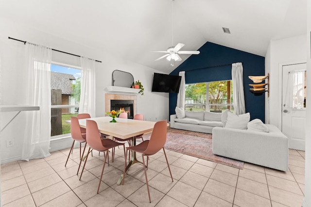 649 Aspen Ln, Cottonwood Shores, TX 78657 - dining area featuring a tiled fireplace, light tile patterned floors, a ceiling fan, lofted ceiling, and plenty of natural light